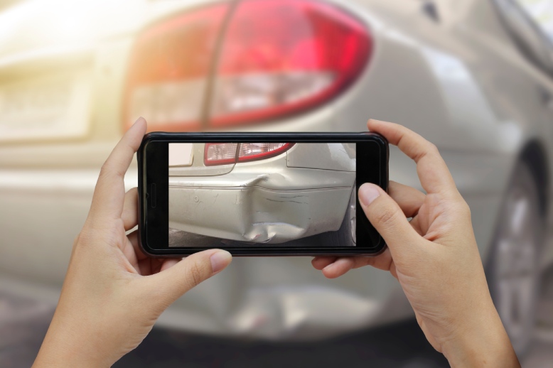 A person taking a photo of a car accident in Valencia with their phone.